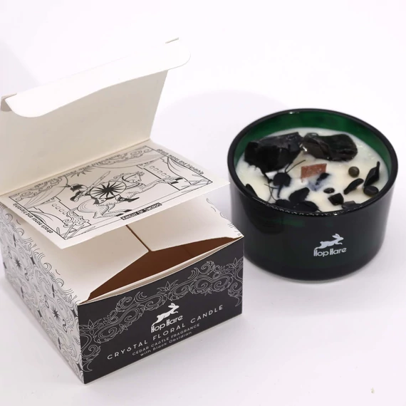 A Kardok Lovagja kristálygyertya obszidiánnal, szárított virágokkal zöld üveg tégelyben, mellette a Hop Hare fekete-fehér tarot-stílusú díszdoboza.